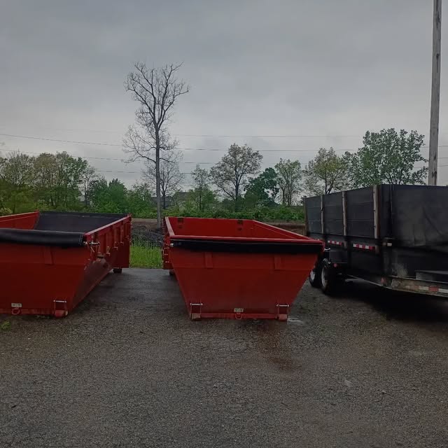 Red roll-off dumpsters alongside a hauling trailer.