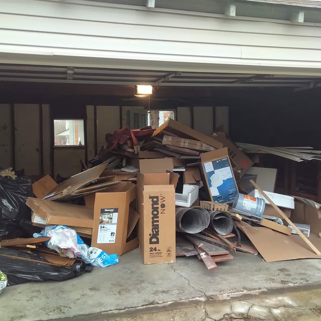 A garage containing stacked cardboard, wood and renovation debris.